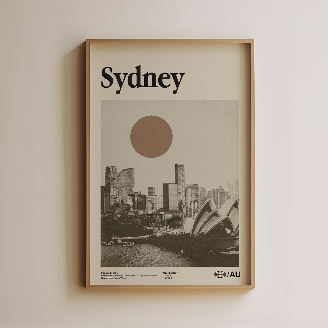 Framed poster of Sydney with a cityscape and sunset on a beige wall.